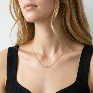 Modèle portant un collier délicat à croix horizontale en argent 925 plaqué or 14k.
