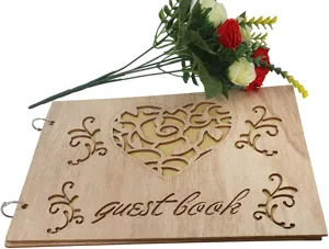 Wooden wedding guest book with heart hollow design and engraved floral details for wedding reception.