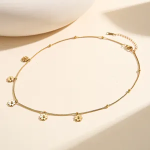Detail shot of a dainty gold stainless steel necklace featuring five small flower pendants