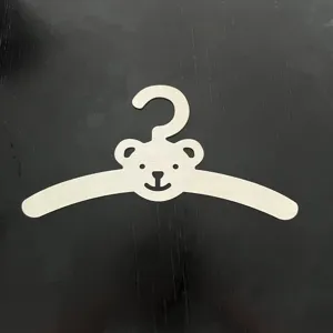 Wooden bear children clothes hanger detail, cute cartoon design for baby room nursery organization.