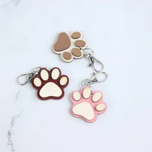 Close-up detail shot of cute wooden paw print keychain with secure metal lobster clasp and smooth edge.