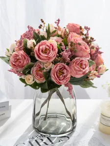 Dettaglio in primo piano di un bouquet di rose rosa artificiali in un vaso di vetro.