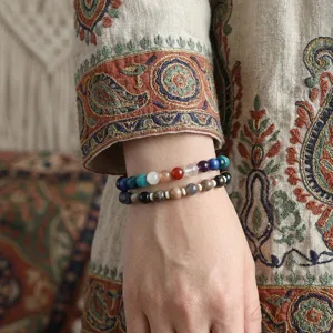 Nahaufnahme von natürlichen Regenbogen-Edelsteinarmbändern an einem Handgelenk mit Boho-Stil.