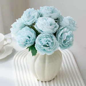 Vue détaillée d'un bouquet de fleurs de renoncules artificielles bleu clair dans un vase blanc.