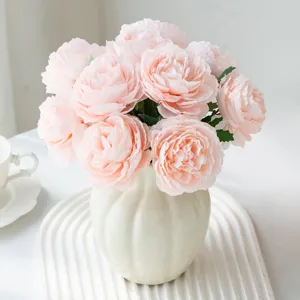 Gros plan de fleurs de pivoine artificielles roses élégantes dans un vase en céramique blanche