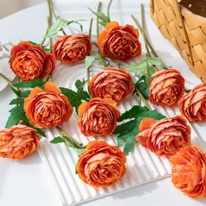 Gros plan détaillé d'un bouquet de fleurs artificielles en soie de renoncules orange.