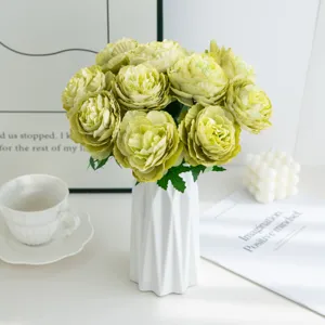 Bouquet de pivoines artificielles vertes dans un vase en céramique blanche pour déco.