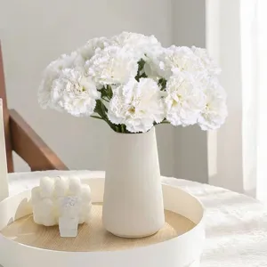Weisse künstliche Nelken Blumen in Keramikvase für Heimdekoration und Hochzeitsfeier.