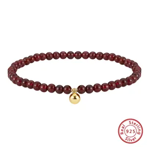 Detail view of a S925 sterling silver natural garnet beaded anklet with gold ball charm