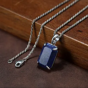 Nahaufnahme Detail eines rechteckigen Lapislazuli Anhängers mit Kette auf strukturierter Fläche.
