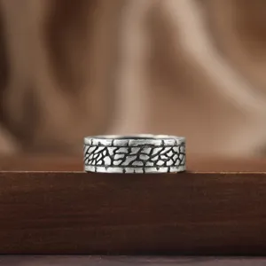 Vue rapprochée d'une bague pour homme en argent noirci avec motif tressé sur bois