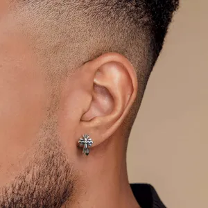 Vue macro d'une boucle d'oreille croix en argent S925 vintage sur une oreille d'homme.