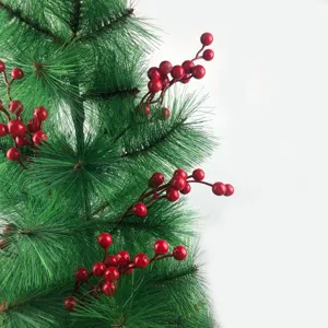 Dettaglio di bacche rosse vivaci su un ramo verde di albero di Natale finto bianco