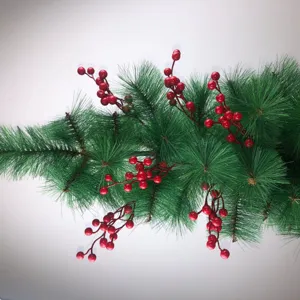 Dettaglio di un ramo di pino natalizio artificiale con bacche rosse di schiuma lucida