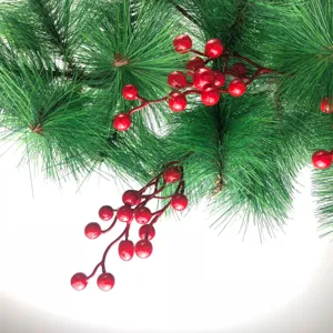 Primo piano di bacche rosse artificiali e aghi di pino per decorazioni natalizie.