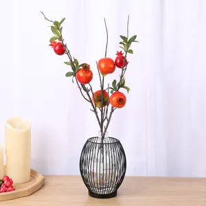 Elegante ramo di melograno artificiale decorativo in un moderno vaso di filo nero per casa