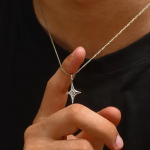 Detailansicht einer silbernen Halskette mit vierzackigem Sternanhänger am Finger.