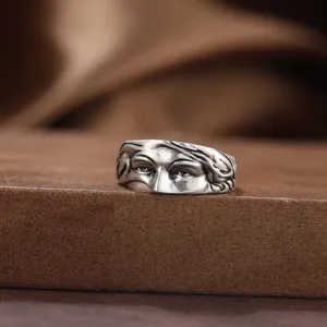 Gros plan d'une bague en argent S925 avec une sculpture complexe de visage humain.
