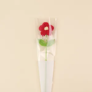 Detailed view of a handcrafted red crochet puff flower inside a 'LOVE' gift sleeve.
