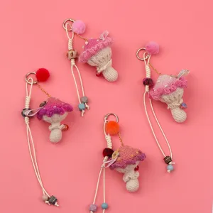 Close-up of handmade crochet mushroom keychains with colorful pom poms on pink background