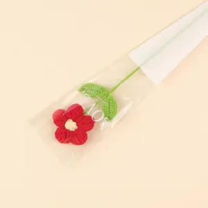 Detailed view of red handmade crochet puff flower in transparent gift packaging with LOVE text