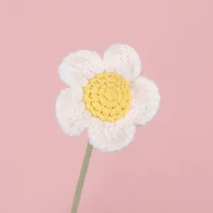 Primo piano di una margherita fatta a mano all'uncinetto in filato bianco e giallo su rosa