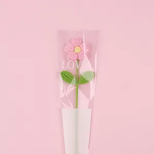 Detailed view of a handmade pink crocheted yarn puff flower in LOVE gift wrap.