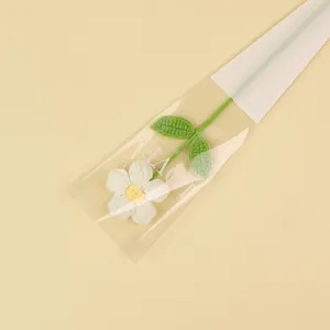 Hand-knitted crochet daisy flower wrapped in transparent decorative sleeve for gift
