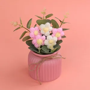 Detailansicht von handgefertigten rosa und weißen Häkelblumen in einem stilvollen Blumentopf