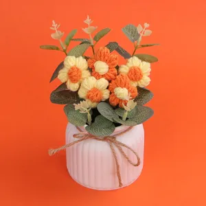 Handgehäkelte Puffblumen in einem weißen Keramiktopf mit einer Juteschleife