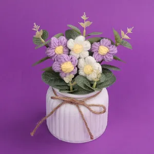 Detailansicht handgestrickter Woll-Puffblumen in einem weißen Keramiktopf mit Kordel