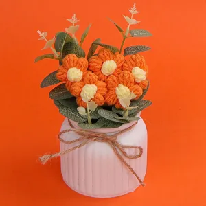 Nahaufnahme eines handgefertigten orangefarbenen Häkelblumentopfs mit Keramiksockel