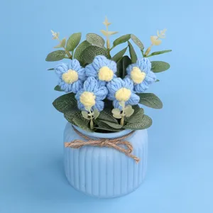 Detailansicht handgefertigter blauer Häkelblumen in einem Topf mit Juteschleife