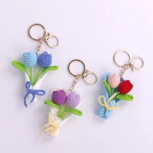 Detail view of three handmade crochet mini tulip bouquet keychains in various colors.
