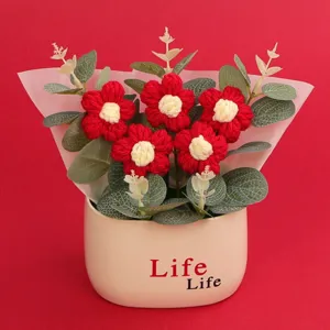 Handmade red and white knitted puff flowers in a cream ceramic pot with Life Life text