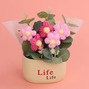Detailed view of a handmade knitted puff flower bouquet in a cream pot with Life print.