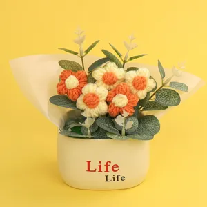 Hand-knitted puff flower potted plant featuring orange and cream yarn flowers