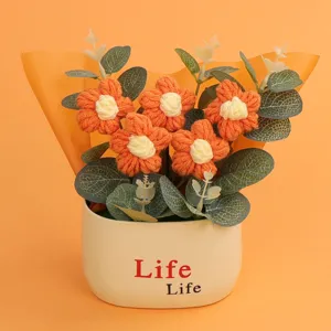 Detailed macro view of hand-knitted orange puff flowers in a cream-colored decorative pot