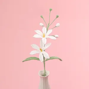 Detailansicht einer fein handgefertigten weißen gehäkelten Orchidee mit grünen Blättern.
