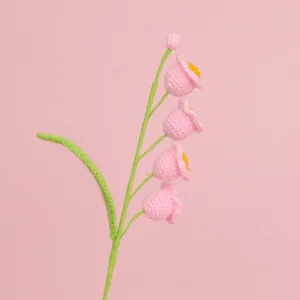 Close-up view of hand-knitted pink Lily of the Valley flowers with soft yarn texture.