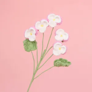Detailansicht der weichen Textur handgehäkelter Stiefmütterchenblumen in Rosa und Weiß