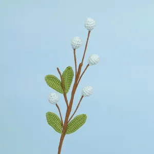 Macro view of handmade crochet flower branch with blue berries and green leaves