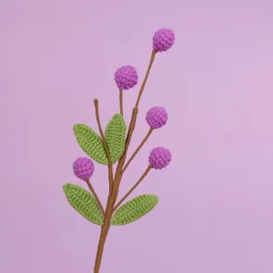 Detailed view of handmade crochet flower branch with purple berries and green leaves