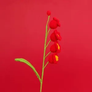Handmade red crochet lily of the valley flower on a vibrant red background for gift