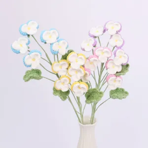 Detailansicht handgehäkelter Stiefmütterchen in weißer Keramikvase als Wohndeko.