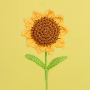 Detail of a handmade crochet sunflower with textured brown center and green stem.