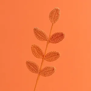 Dettaglio di uno stelo di foglie all'uncinetto arancione fatto a mano per fiori