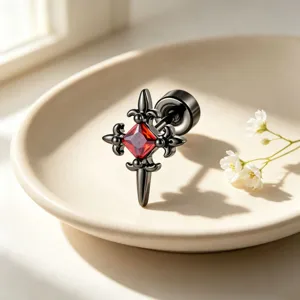 Close-up detail of a gothic black cross earring with a brilliant red square zircon stone