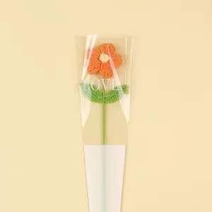 Hand-knitted orange yarn puff flower in LOVE transparent sleeve for home decor gift.