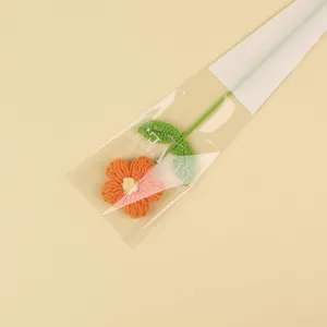 Detail shot of a handmade orange crocheted puff flower inside transparent gift packaging